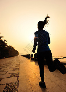 赛跑运动员在海边女子健身慢跑环绕太阳日出健图片