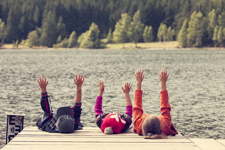 三名儿童坐在湖边浮水船图片