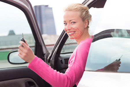 年轻女为她的新车或驾驶执照而快乐地开车图片