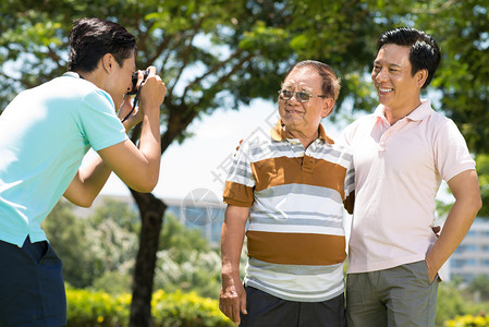 在公园前台拍摄他父亲和祖父照片的画面图片