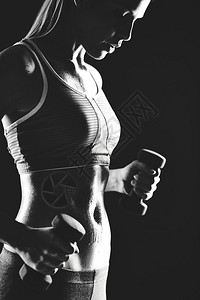穿着运动服的苗条女用哑铃锻炼的形象图片