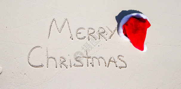 白沙滩上的圣塔帽和圣诞快图片