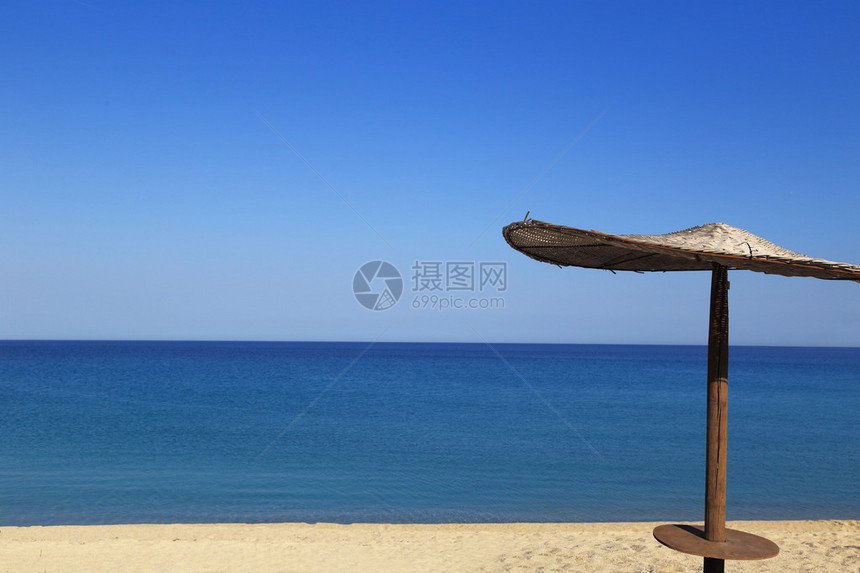 有柳条伞的晴朗的海滩图片