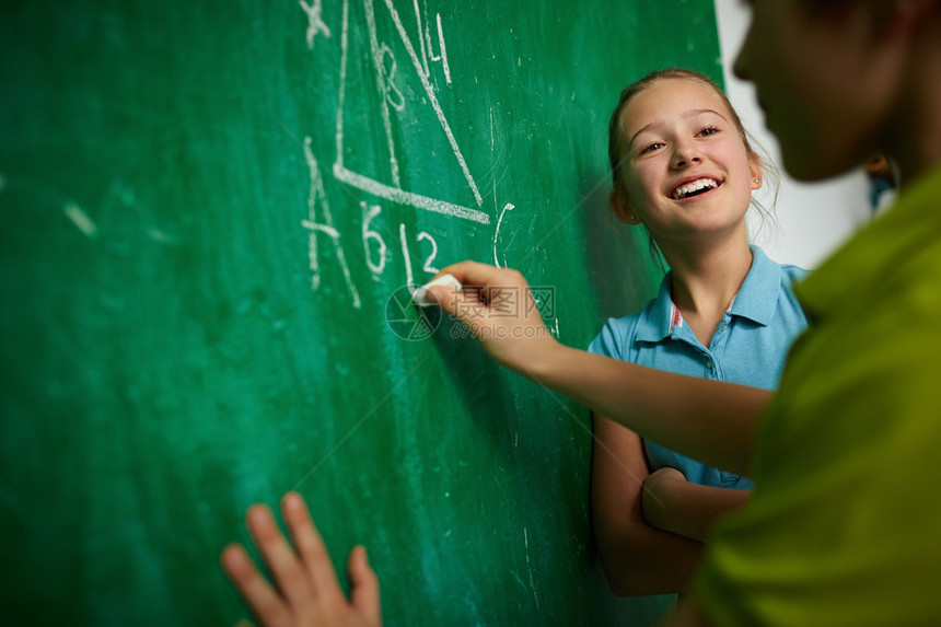 快乐的女孩在几何课上在黑板旁看着她的同学图片