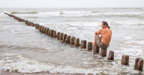 中年人坐在海边若有所思地望着远方图片
