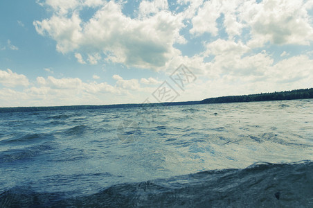 蓝色多云的天空下森林湖泛起涟漪的冷水图片