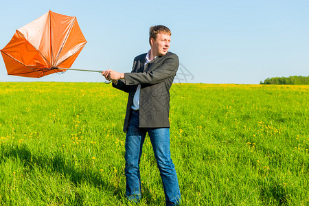 强风拧橙色雨伞的人图片