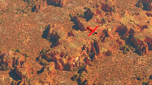 红色飞机在干燥的红色沙漠景观上空飞行图片