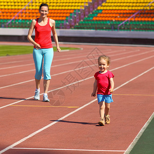 母亲和小女儿在体育场跑来去孩子在体育图片