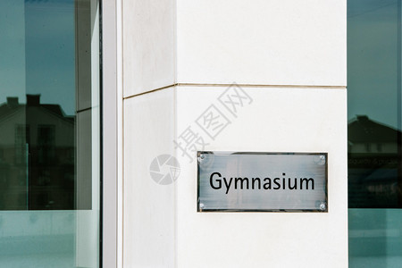 在提供高级中等教育的学习环境入口处一面大理石墙上的体育学校标志图片