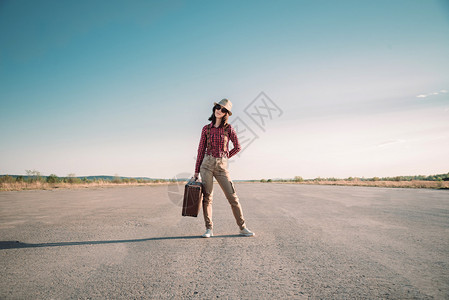 随行的时装女潮人站上路用旧式行李箱背景图片