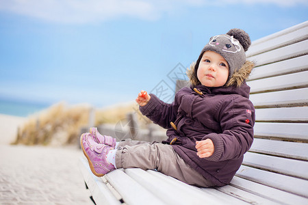 蹒跚学步的孩子在北海坐得更冷图片