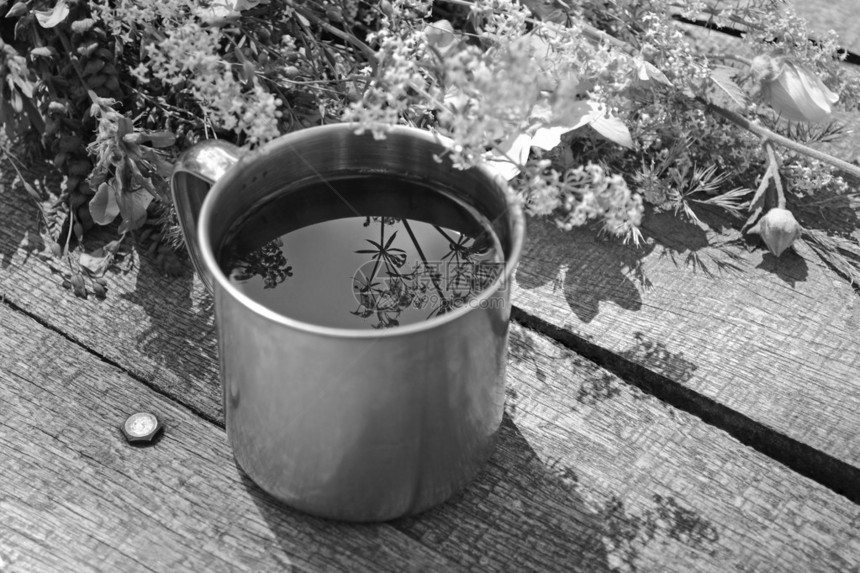 灰色木桌上的钢制营地茶杯上面放着鲜花图片