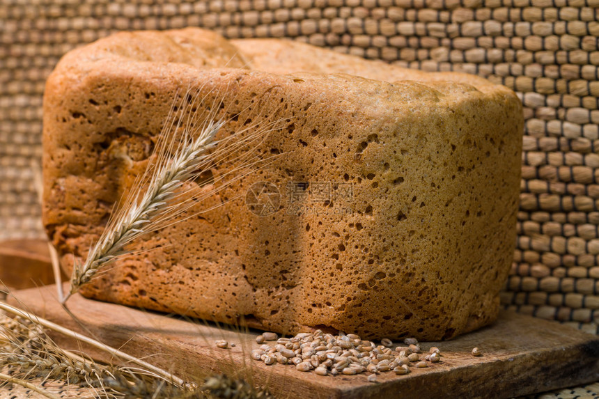木板上的新鲜小麦面包和小麦对传图片