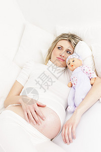 孕妇抱着洋娃躺在床上背景图片