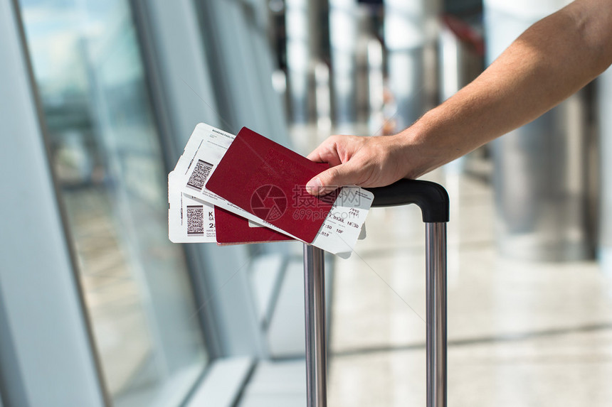 男子持护照和登机牌在机场的特写图片