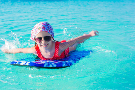 小女孩在绿松石海的冲浪板上游泳图片