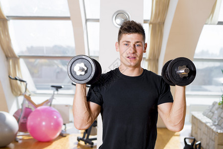 男子在健身房用哑铃锻炼图片