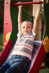 可爱的小男孩即将在儿童游乐场的滑梯上乘坐滑梯图片