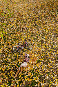 秋叶骑自行车的年轻女子图片