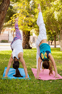 年轻女在公园做瑜伽时练习站立劈叉图片