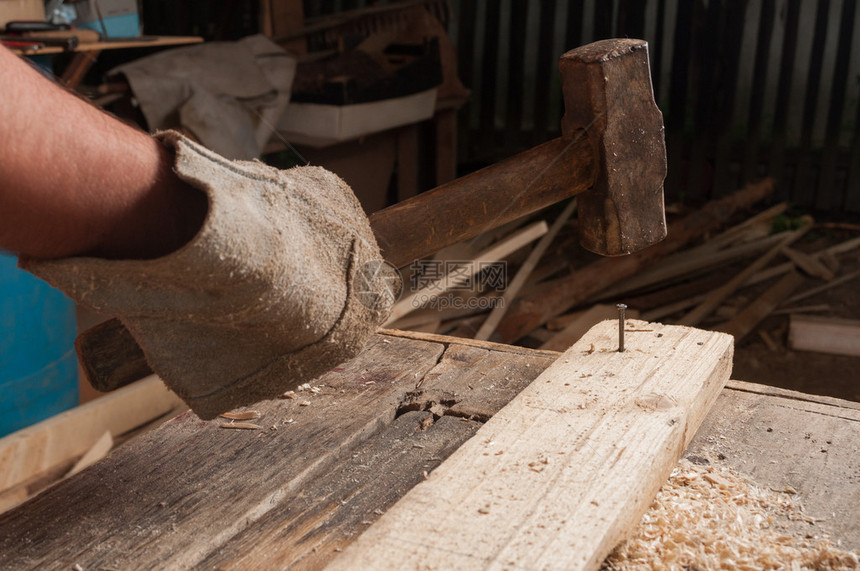 男木匠在他的工作室里用大锤子在木头上敲钉子图片