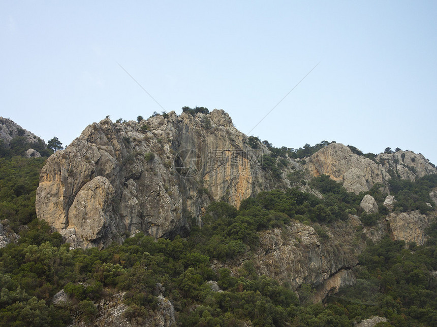 落日余晖中的岩石峭壁山树和蓝天图片