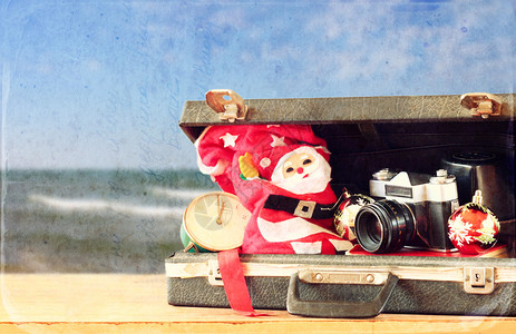 在海滩观光前开具带有圣诞节装饰和照相机的公文包圣图片