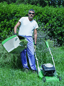 男人在他的院子里修剪杂草丛生的草坪图片