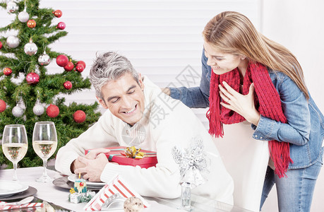 40多岁的男人把圣诞礼物藏到妻子手里开玩笑和放图片