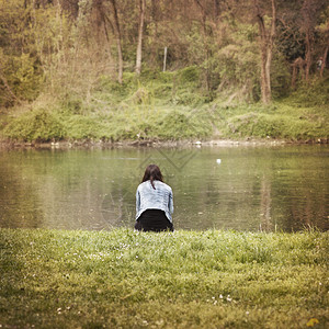 一个女孩坐在河岸附图片