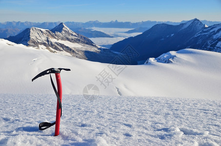 冰斧卡在冰川上方高山的雪中图片