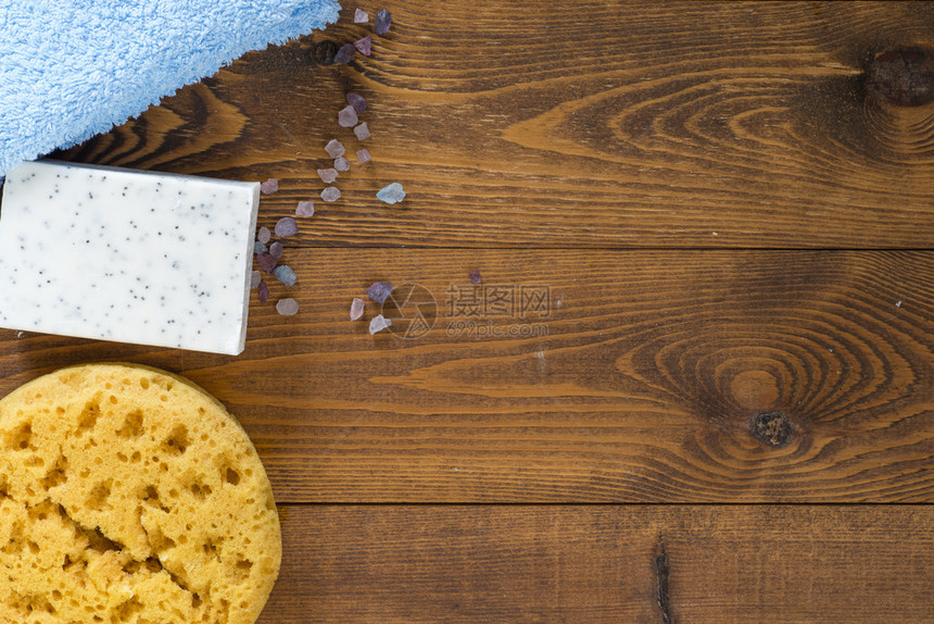 海绵肥皂海盐和木制背景上的蓝色毛巾图片