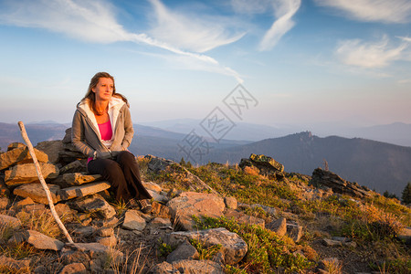 美丽的女人坐在一块石头上看着从俄勒冈红毯子山顶的日图片