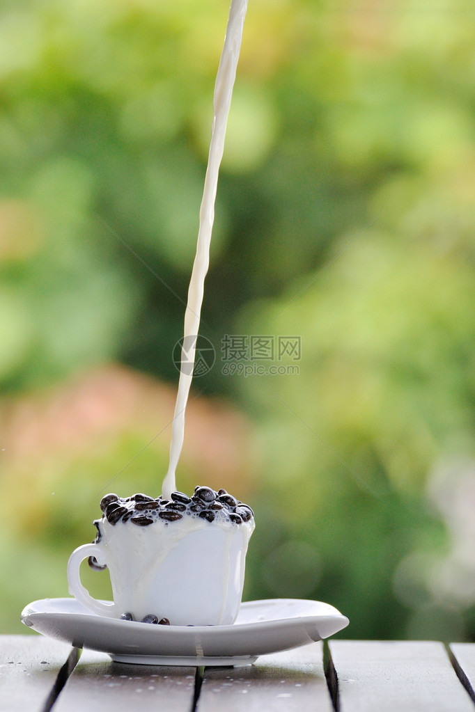 白杯中的咖啡籽和倾吐的鲜奶图片