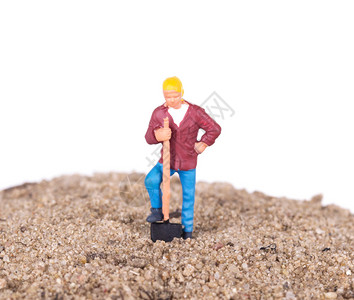用铁锹在沙山上的微型工人图片