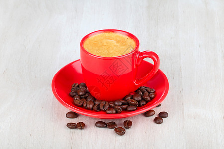 木桌上的红杯咖啡和咖啡豆图片
