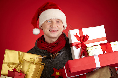 圣诞老人帽的快乐男人的肖像带着满的礼物图片