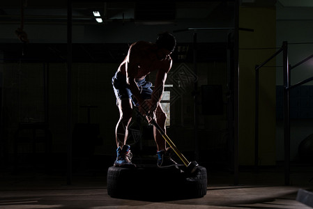 运动男子打轮胎在健身房用锤子和拖拉机轮胎Sil图片