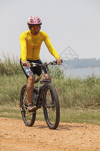 身穿骑车西装的青年男子乘山上自行车MBT骑在沙尘路上用于体育活动和图片