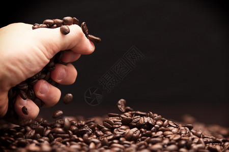 高反差的画面是手抓着咖啡豆一些被扔到图片