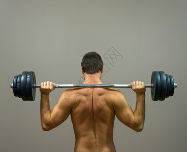 用杠铃锻炼的肌肉男后视图图片