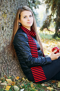 美丽的女人有一个苹果坐在树图片