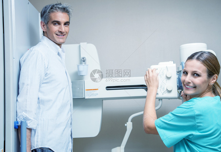 40多岁的男病人在微笑美丽的女医生的协助下接受了X光检查医院的现场图片