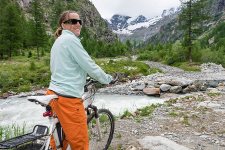 妇女骑自行车者享受山图片