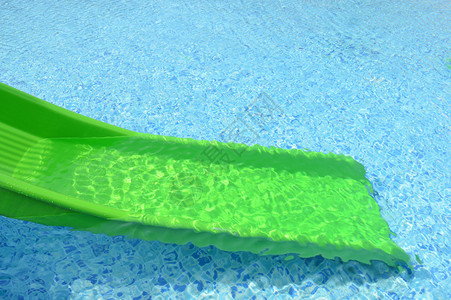 游泳池前的绿色塑料滑块图片