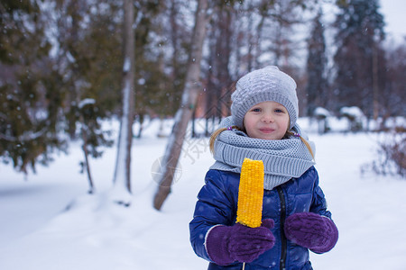 小女孩在冬日户外吃玉米图片