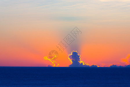 蓝色海平面的云层后面升起的太阳浪漫多彩的天图片