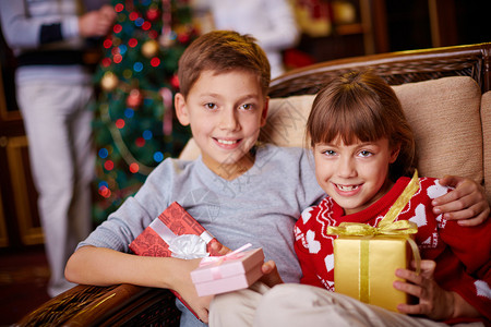 两个快乐的孩子的肖像圣诞礼物看着摄影图片