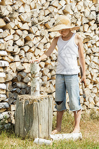当地农场伐木时的少年男孩在本地农场从图片